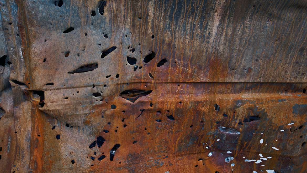 Bullet and shrapnel holes in carcass of destroyed car