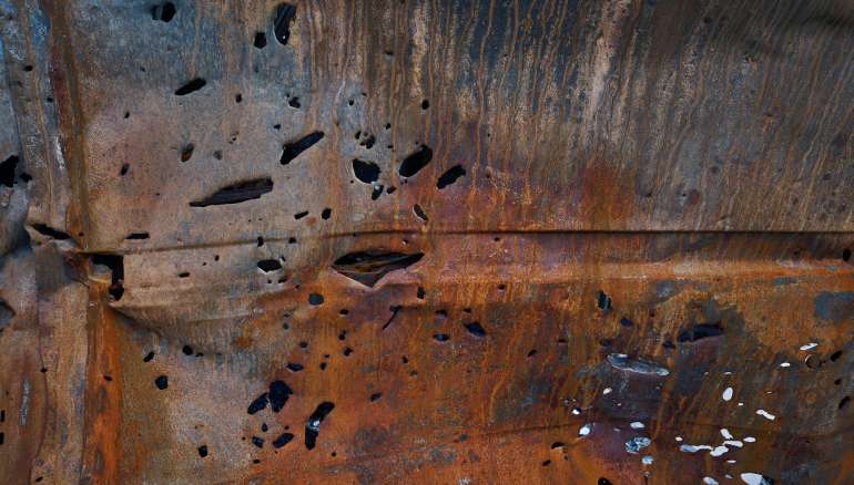 Bullet and shrapnel holes in carcass of destroyed car